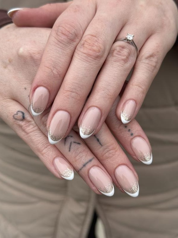 Almond nude nails with white French tips and a fine glitter line
